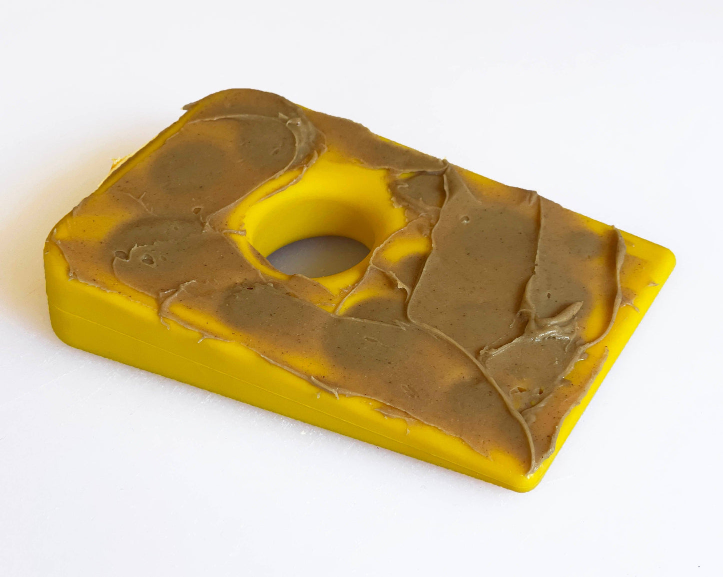 Yellow Swiss cheese dog chew toy with soft food spread into the holes for enrichment play