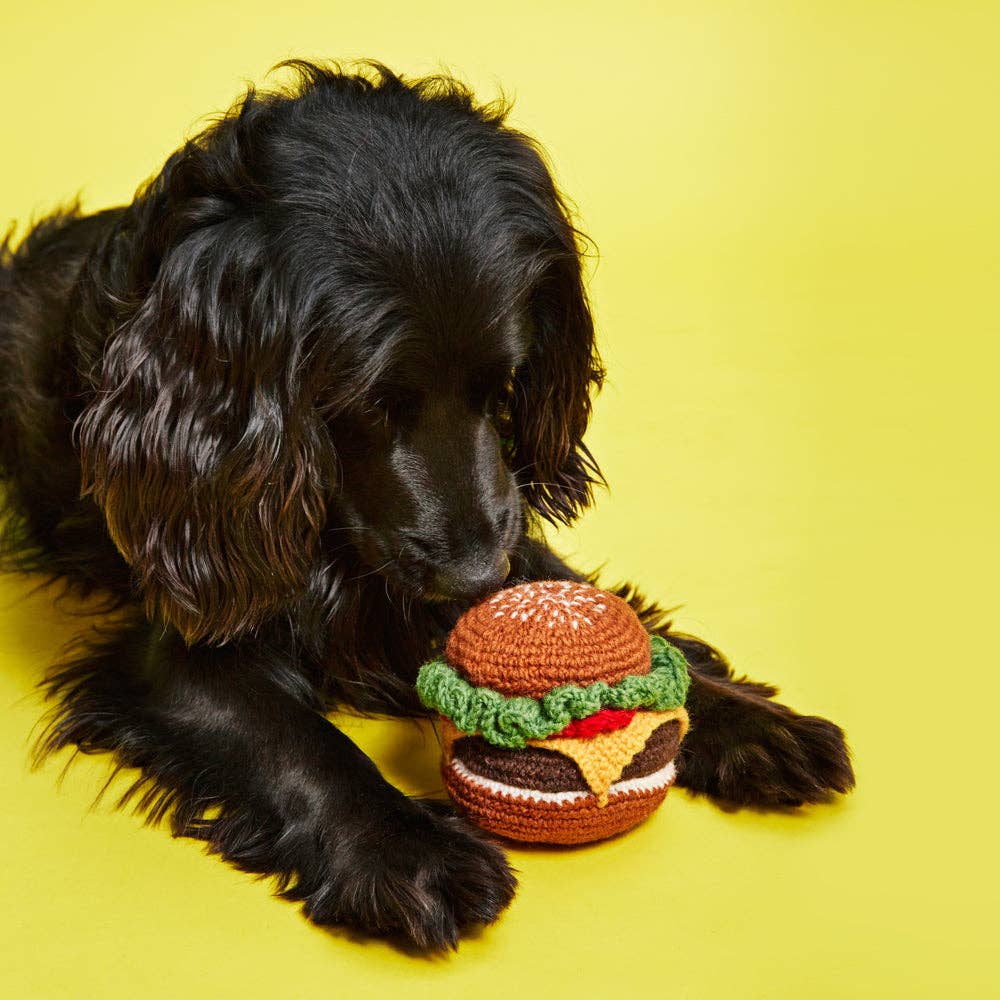 Dog playing with a lambswool hamburger dog toy made with non-toxic dyes and sustainably crafted materials