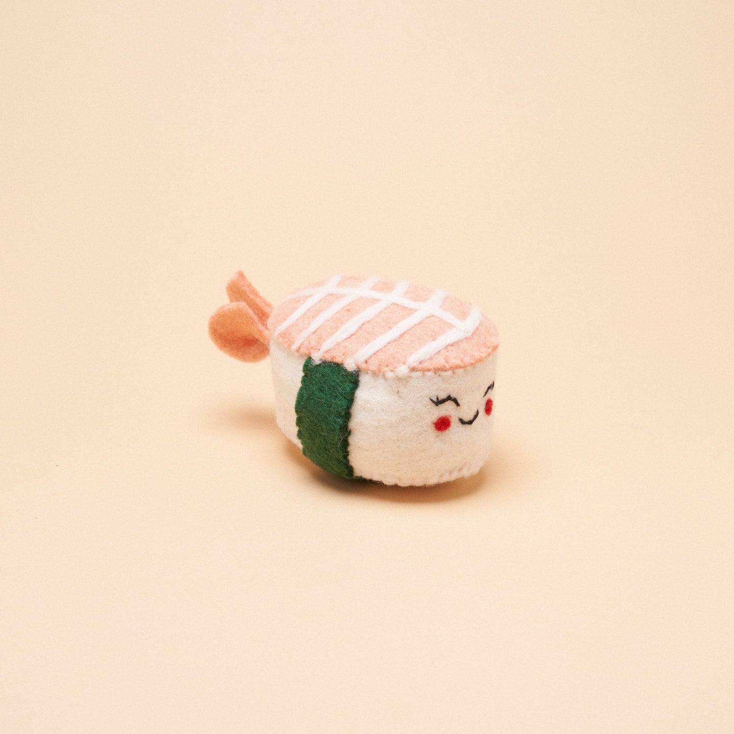 A handmade, shrimp nigiri-shaped dog toy made from 100% natural wool. 