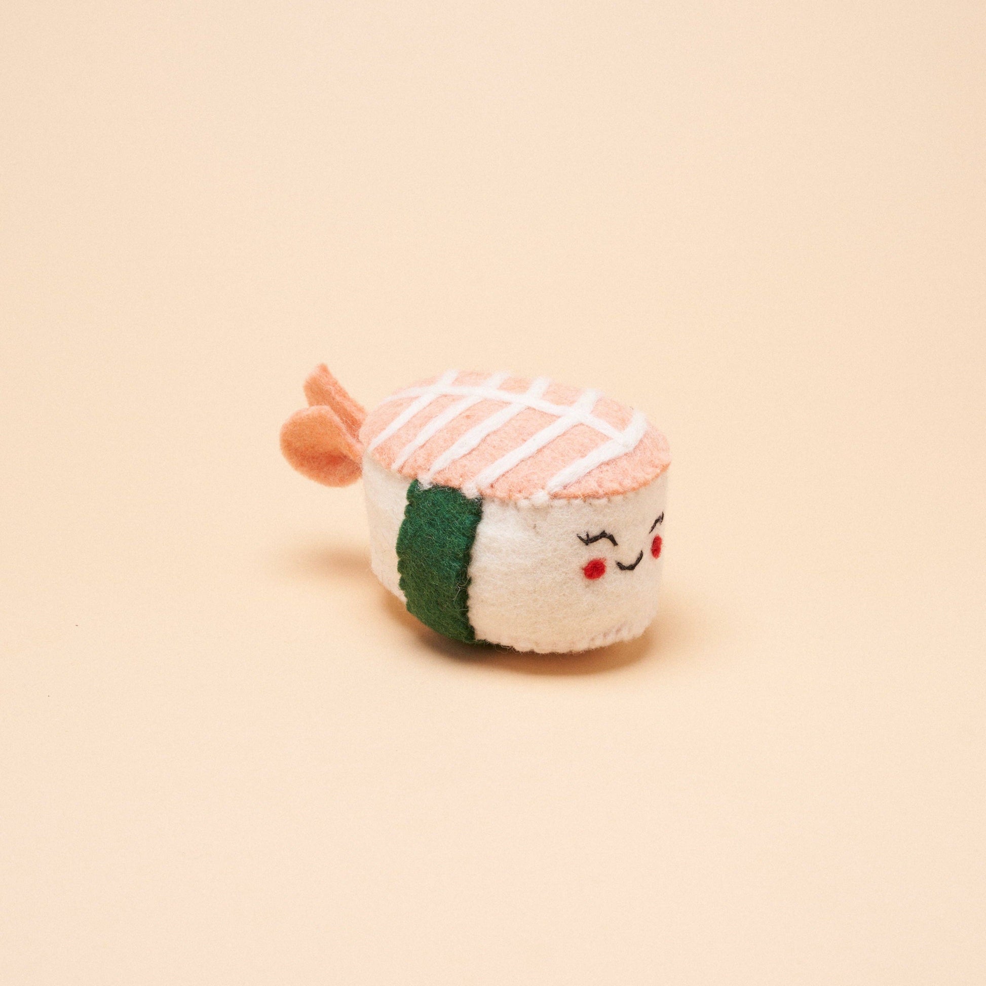 A handmade, shrimp nigiri-shaped dog toy made from 100% natural wool. 