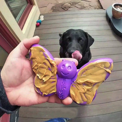 Dog playing with the SodaPup Butterfly Enrichment Chew Toy outdoors with peanut butter, designed for power chewers.
