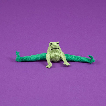 A green organic cotton frog dog toy against a purple background.